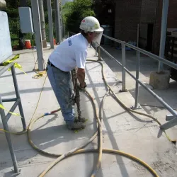 Working applying epoxy pressure injection grouting to a cracked concrete foundation